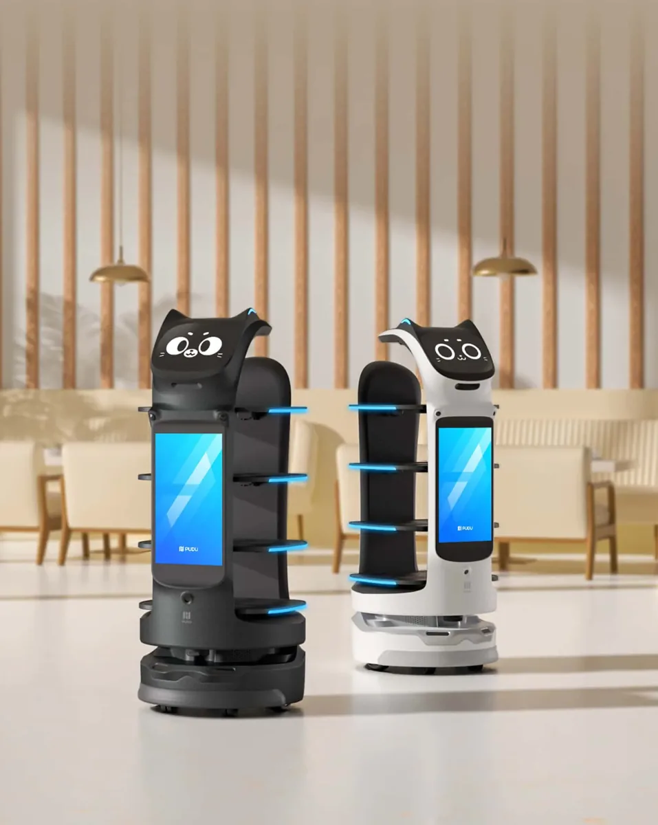 Two BellaBot Pro delivery robots, one black and one white, in a hotel restaurant